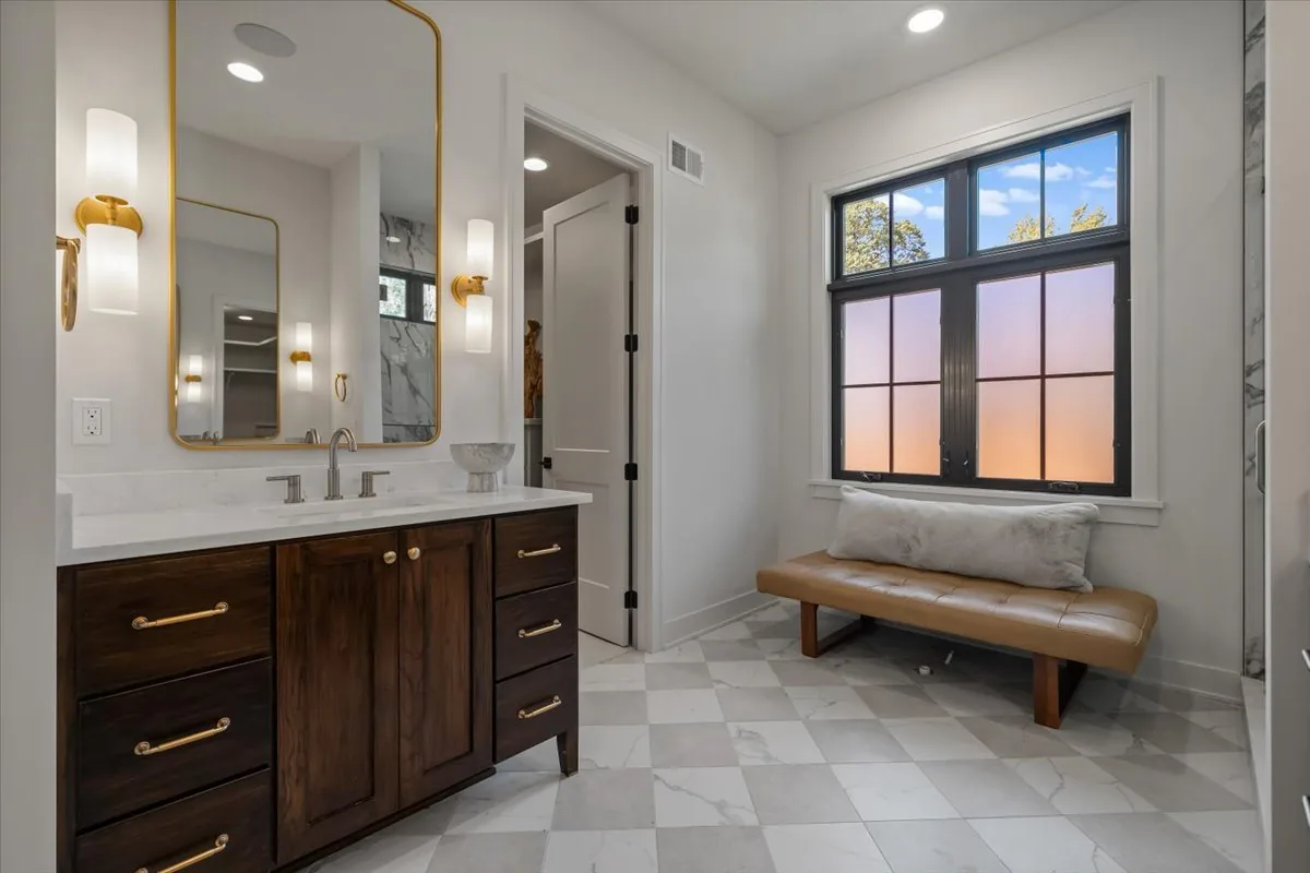 Primary bath with dark vanity, brass fixtures and checkerboard tile floor