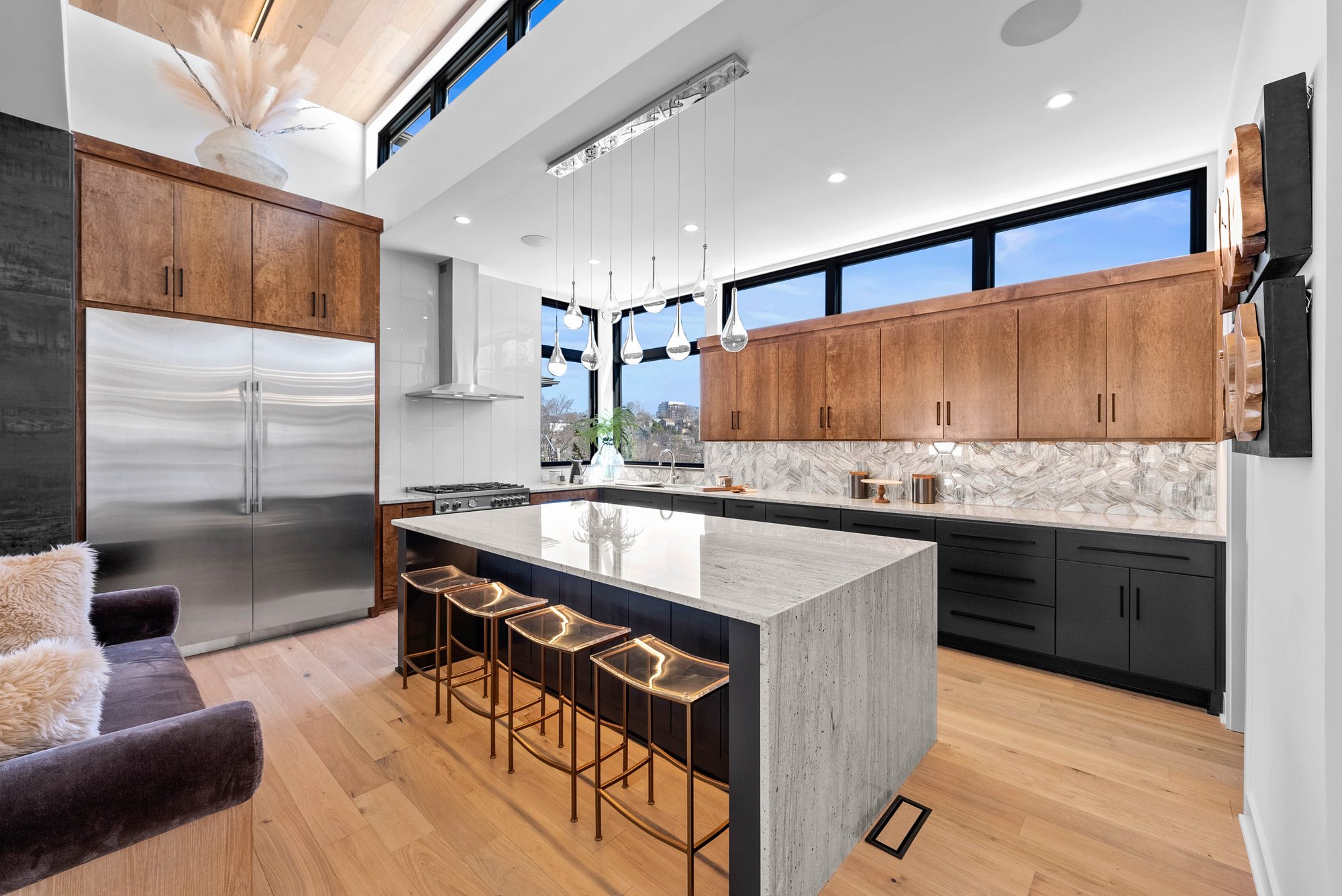 Custom kitchen with wood cabinetry, stone island and city view windows