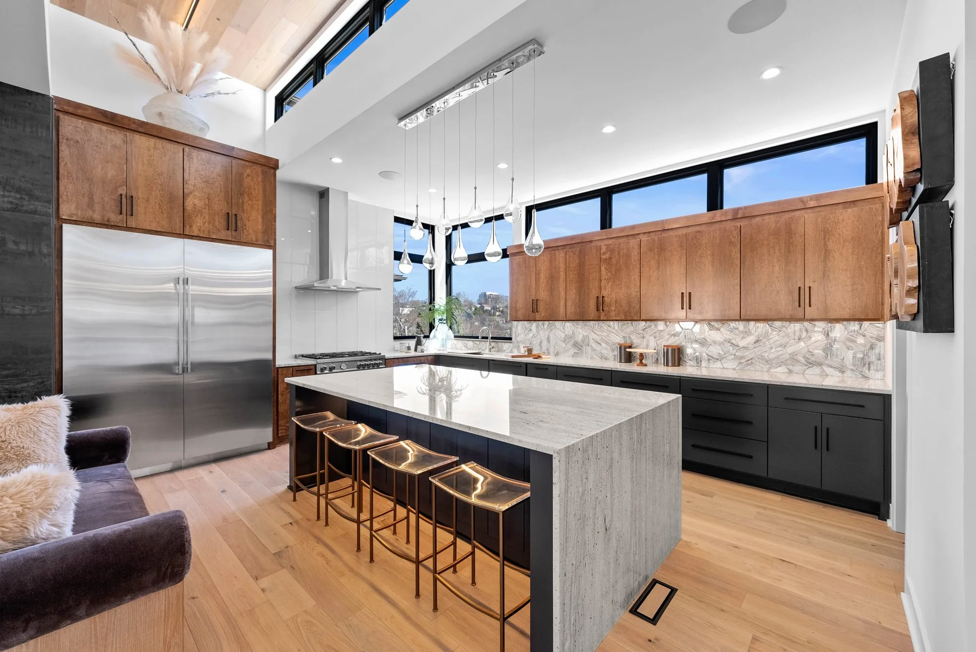 Custom kitchen with wood cabinetry, stone island and city view windows