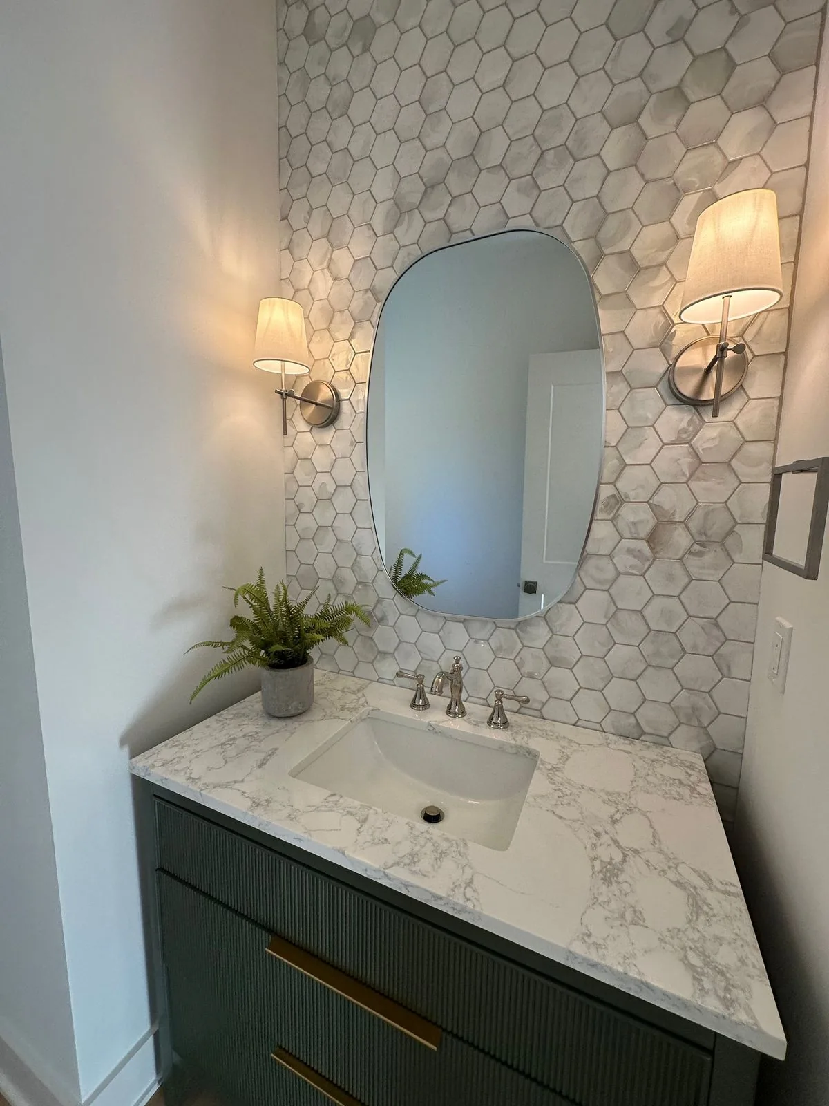 Powder room with hexagonal tile wall and arched mirror