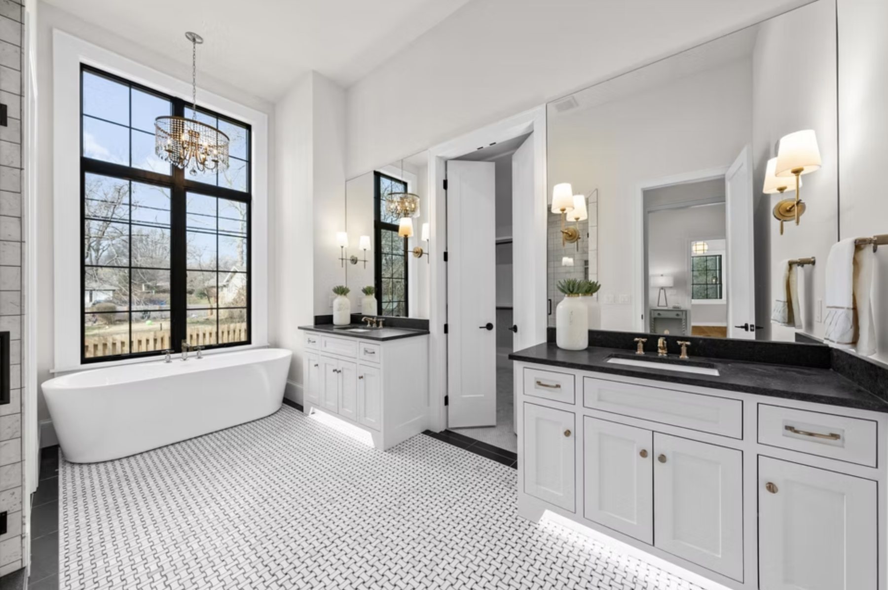 Primary bath with freestanding tub, chandelier and tall windows