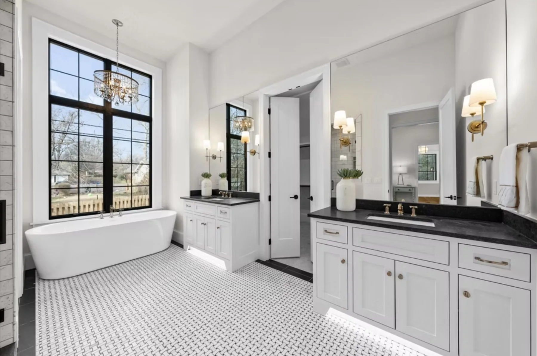 Primary bath with freestanding tub, chandelier and tall windows